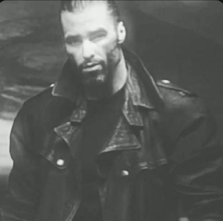Man in leather jacket striking a confident pose.